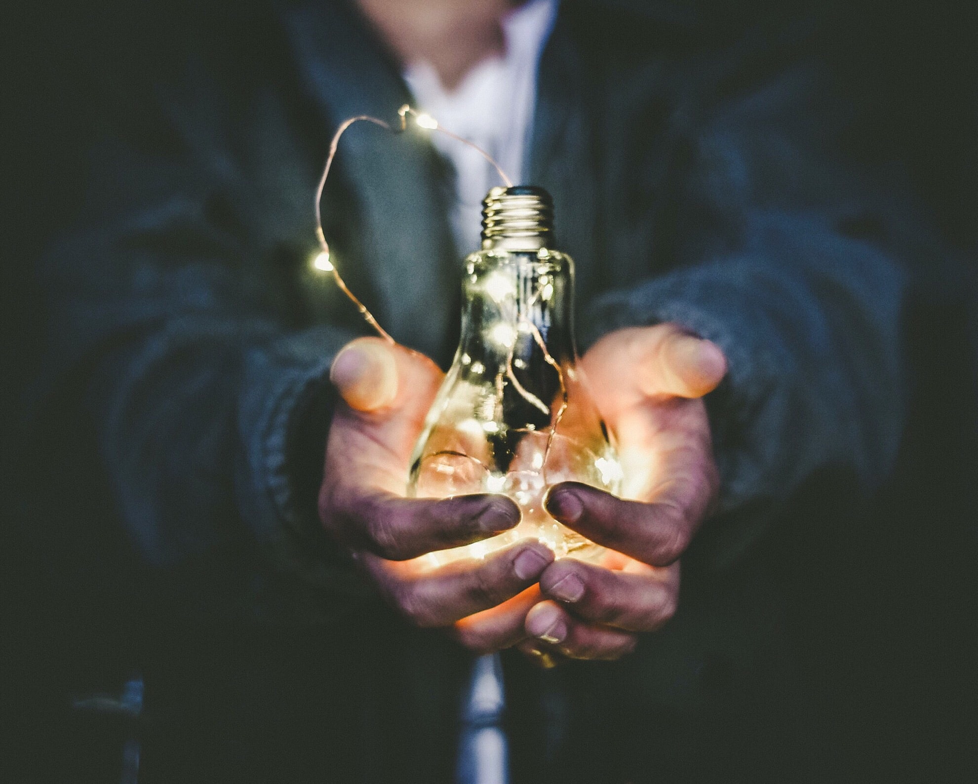 person holding a light bulb that has fairy lights inside